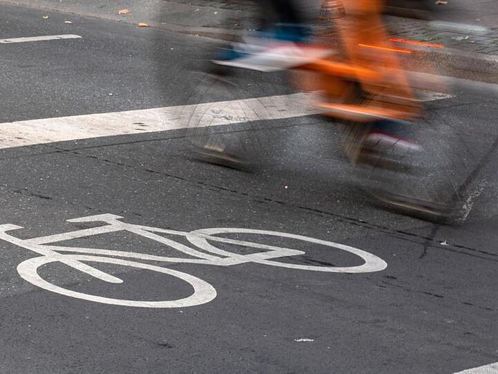 Ein Fahrradfahrer fährt in der Innenstadt über einen Radweg.