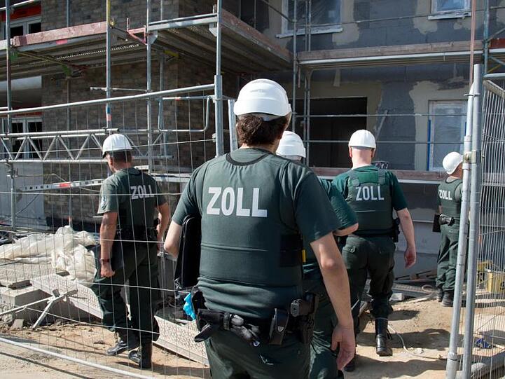 Zollbeamte betreten bei einer Razzia gegen Schwarzarbeit eine Baustelle.