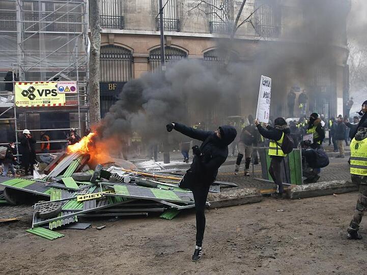 Ein Demonstrant in Paris bewirft die Polizei.