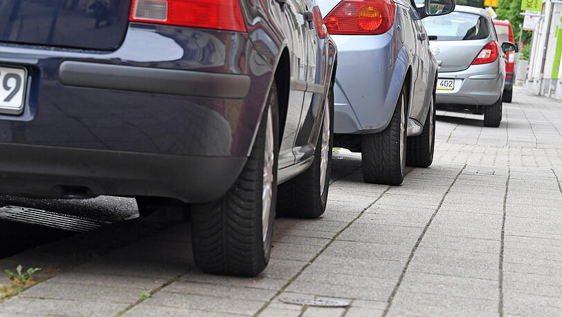 Autos parken "halbseitig" auf einem Gehweg. (Symbolbild)