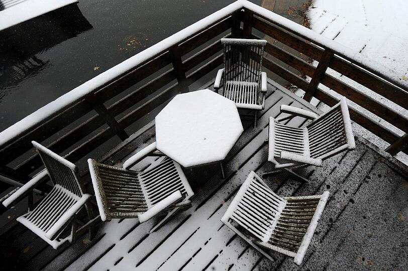 Mit Schnee bedeckt ist am Samstag ein Tisch, der auf einer Veranda am Ufer des Spitzingsees steht.