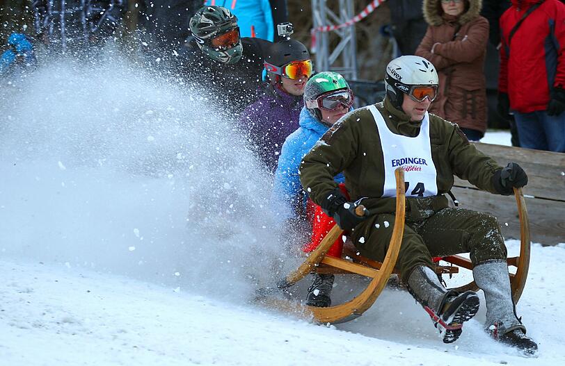 Teilnehmerinnen des traditionellen Hornschlittenrennes fahren in Garmisch-Partenkirchen die Piste hinab.