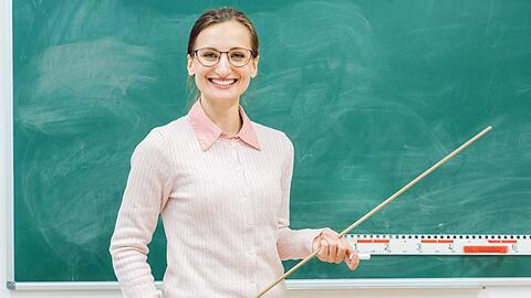 Eine Lehrerin an der Tafel. Bei Lehrern fällt der Unterschied bei der Lohnfortzahlung zwischen Beamten und Angestellten besonders ins Auge.