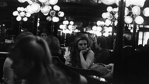 Ein Restaurant im "Citta 2000" im Jahr 1974: Eine junge Frau sitzt zwischen anderen Gästen und unter auffälligen Lampen.