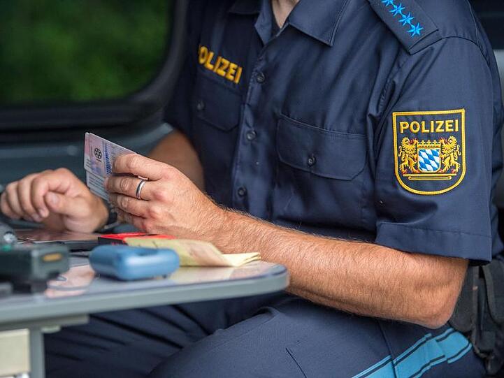Ein Beamter der bayerischen Grenzpolizei kontrolliert am Grenzübergang Kirchdorf Dokumente von Autofahrern. Foto: Lino Mirgeler/dpa/Archiv