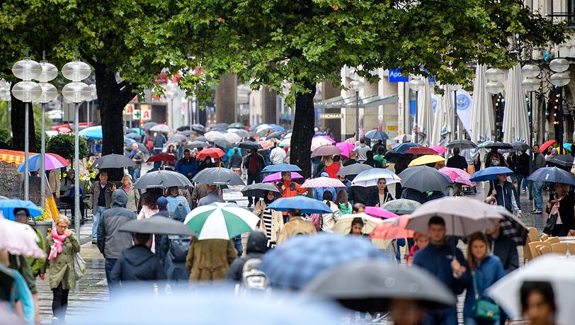 Passanten mit Regenschirmen laufen im Regen durch die Fußgängerzone Neuhauser Straße und Kaufingerstraße nahe dem Stachus in München.
