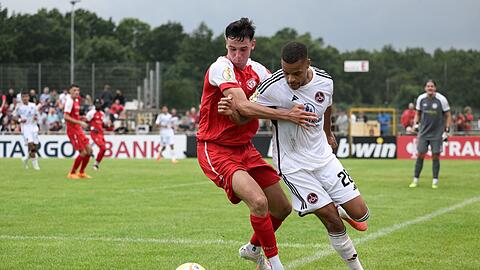 Jan Gyamerah (r) aus Nürnberg wird während des Versuchs einer Flanke von einem Spieler von Oberneuland gestört.