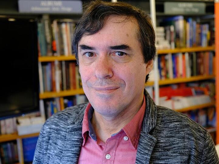 Mircea Cartarescu steht vor einer Bücherwand in der Buchhandlung Humanitas. Foto: Birgit Zimmermann/Archiv
