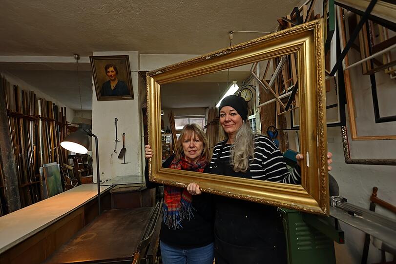 Drei starke Damen im Werkstattladen von Rahmen Müller: Gründergattin Sophie Müller (oben an der Wand), die neue Chefin Bettina Treutler (r.) mit Vorgängerin Gaby Fesl.