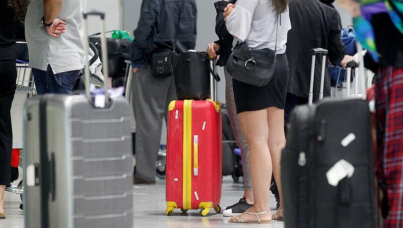 Fluggäste warten vor einem Check-In-Schalter am Düsseldorfer Flughafen auf ihre Abfertigung.