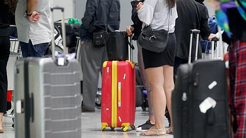 Fluggäste warten vor einem Check-In-Schalter am Düsseldorfer Flughafen auf ihre Abfertigung.