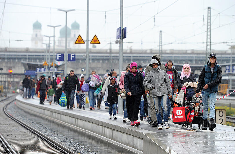 Diese Flüchtlinge gehen über einen Bahnsteig auf dem Bahnhof in Passau (Bayern). Sie waren mit einem Zug aus Österreich gekommen und mussten in Passau den Zug verlassen, um sich vor der Weiterreise registrieren zu lassen.