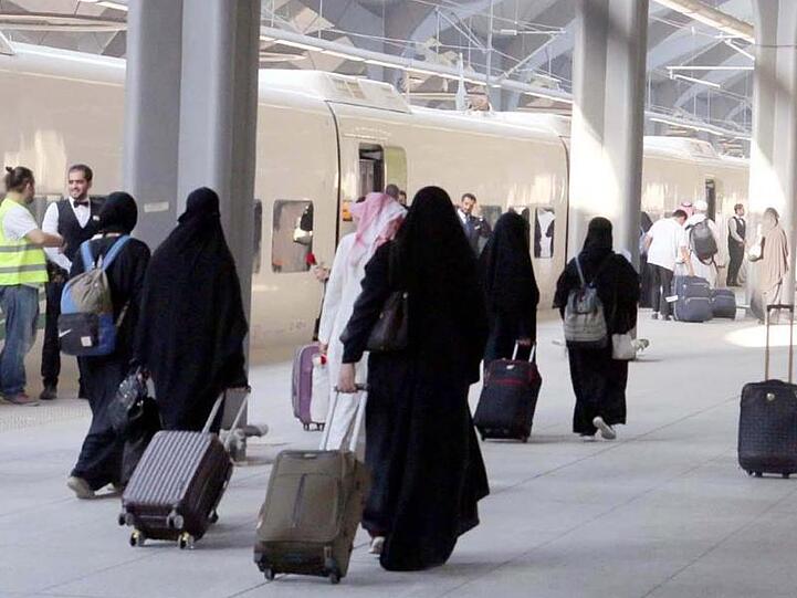 Saudische Frauen mit Ganzkörperschleier ziehen ihre Rollkoffer über einen Bahnsteig in Medina.