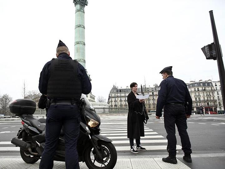Polizeibeamte kontrollieren die Ausgangsformulare an einer Kontrollstelle in Paris.