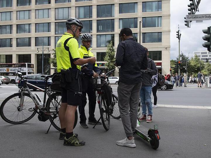Und noch eine neue Aufgabe: Polizisten der Berliner Fahrradstaffel kontrollieren auf einem Bürgersteig zwei Jugendliche mit E-Tretrollern.