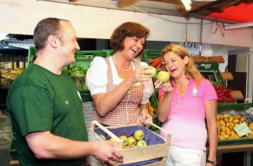 Wenigstens ein schönes Foto, wenn schon keine Wähler zum Wahlkampftermin kamen: Ilse Aigner und Mechthilde Wittmann strahlen mit zwei deutschen Äpfeln und Standl-Besitzer Karl Huczala