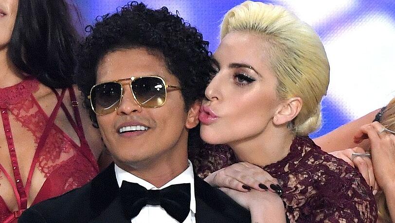 Bei der Victoria's Secret Fashion Show in Paris gab es für Bruno Mars ein Küsschen von Lady Gaga. Bald steht das Duo zusammen auf der Bühne.