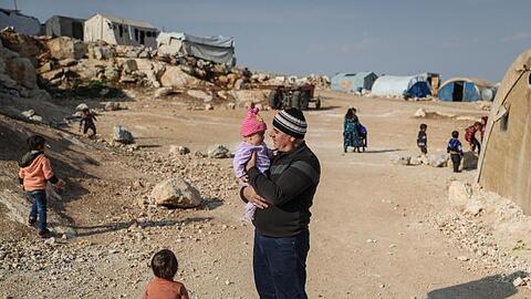 Ein Mann steht mit seinen Kindern in einem Flüchtlingslager in der Provinz Idlib.