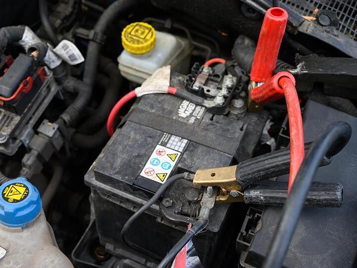 An einer Autobatterie klemmen Starthilfekabel.