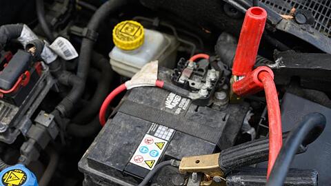 An einer Autobatterie klemmen Starthilfekabel.