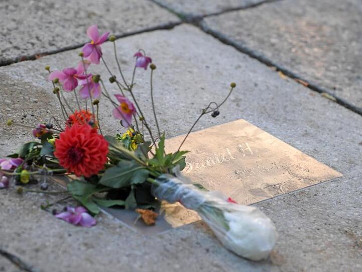 Blumen liegen an einer Gedenkplatte für den getöteten Daniel H. in Chemnitz.