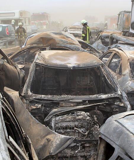 Feuerwehrleute sind am Freitag auf der Autobahn A19 bei Kavelstorf in der Nähe von Rostock bei einer Massenkarambolage im Einsatz. Bei einem Sandsturm fuhren in beiden Fahrtrichtungen Dutzende Fahrzeuge und LKW ineinander und brannten teilweise aus.