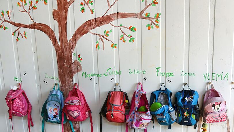 Rücksäcke von Kindern hängen an einer Wand in einer Kita. (Archivbild)
