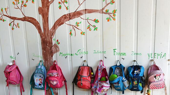 Rücksäcke von Kindern hängen an einer Wand in einer Kita. (Archivbild)