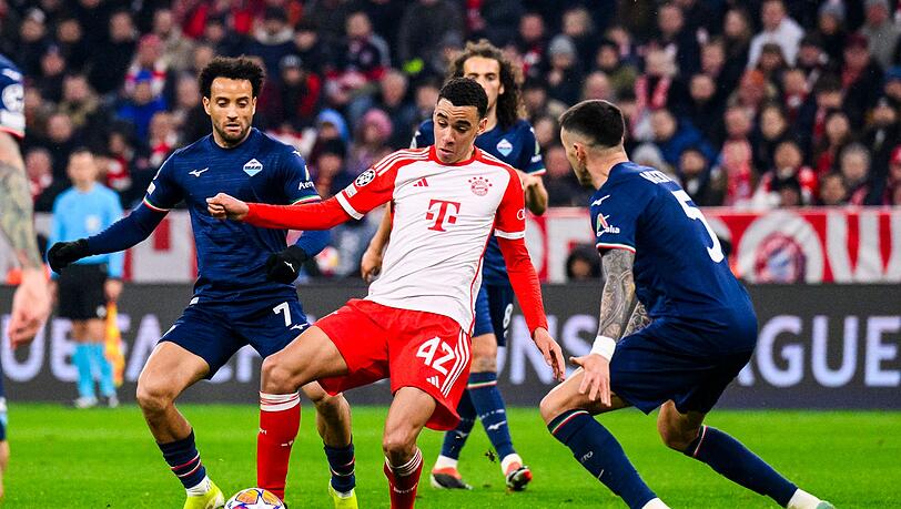 Münchens Jamal Musiala (M) in Aktion gegen Roms Felipe Anderson (l) und Roms Mataas Vecino (r).