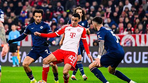 Münchens Jamal Musiala (M) in Aktion gegen Roms Felipe Anderson (l) und Roms Mataas Vecino (r).