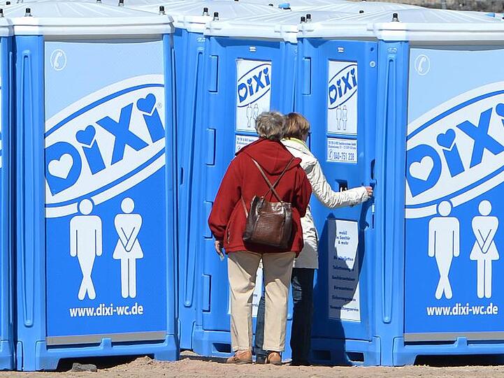 Zwei Frauen stehen vor Dixi-Klos in Hamburg. Foto: Marcus Brandt/dpa/Archivbild
