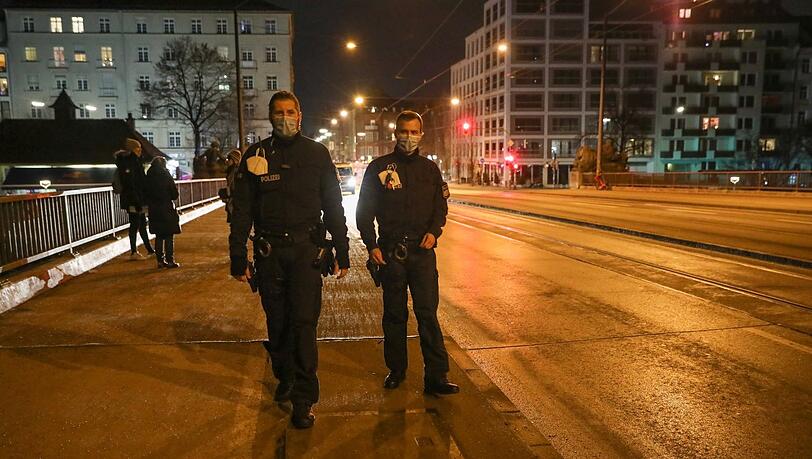 Kurz vor Mitternacht auf der Reichenbachbrücke: Zwei Beamte schauen zur Kontrolle vorbei - drunter rauscht die Isar.