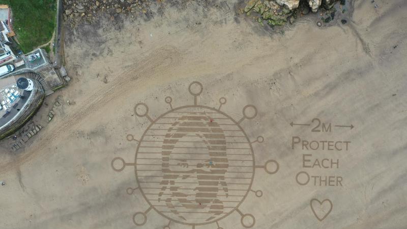 Am Strand in der Stadt Whitby wurde in den Sand ein riesiges Kunstwerk gemalt, das auf den Mindestabstand von zwei Metern während der Corona-Pandemie hinweist. Am Strand in der Stadt Whitby wurde in den Sand ein riesiges Kunstwerk gemalt, das auf den Mindestabstand von zwei Metern während der Corona-Pandemie hinweist.