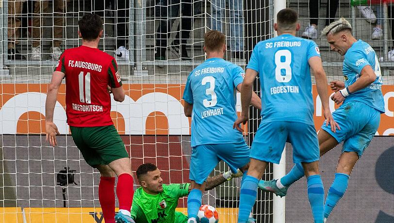 Augsburgs Michael Gregoritsch (l) und Torwart Rafal Gikiewicz können das 1:2 durch Freiburgs Nico Schlotterbeck (r) nicht verhindern.