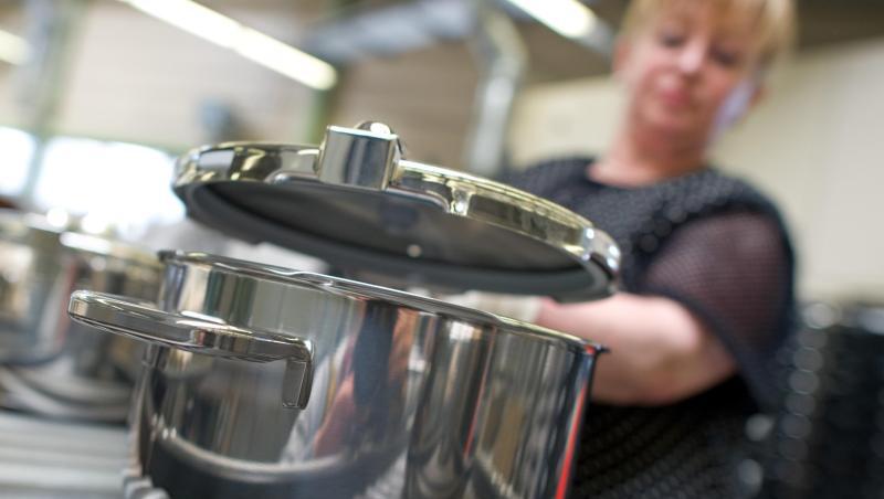 Eine Mitarbeiterin setzt im Stammwerk des Küchengeräteherstellers Württembergische Metallwarenfabrik AG (WMF) in Geislingen einen Deckel auf einen fertiggestellten Topf. Eine Mitarbeiterin setzt im Stammwerk des Küchengeräteherstellers Württembergische Metallwarenfabrik AG (WMF) in Geislingen einen Deckel auf einen fertiggestellten Topf.