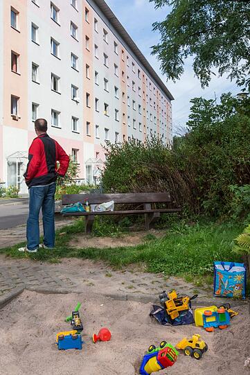 Spielzeug liegt in einem Sandkasten vor dem Gebäude.