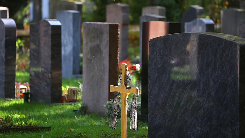Der Friedhof als (bisheriger) Standard der Trauer: Ein Kreuz steht vor Grabsteinen in Augsburg.