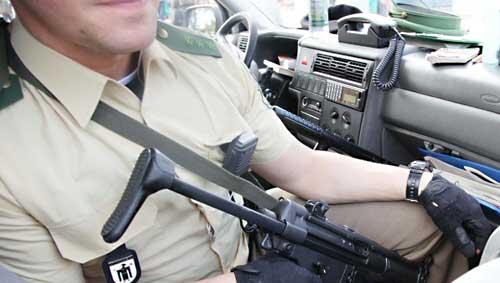 Die Waffe im Anschlag überwacht ein Polizist von seinem Streifenwagen aus die Theresienwiese.