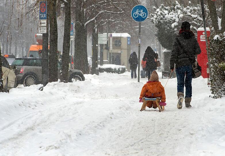 Wunderbare Winterwelt: Eine Mutter zieht ihr Kind auf dem Schlitten hinter sich her.