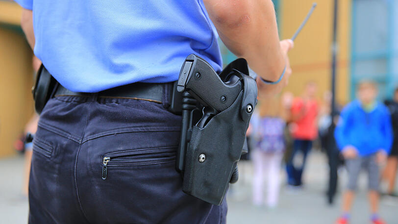 Ein Polizist steht auf dem Gelände einer Schule (Symbolbild).