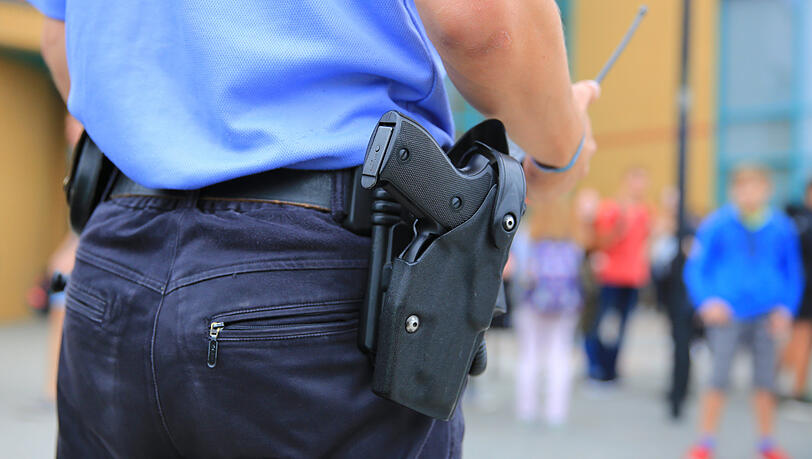 Ein Polizist steht auf dem Gelände einer Schule (Symbolbild). Ein Polizist steht auf dem Gelände einer Schule (Symbolbild).