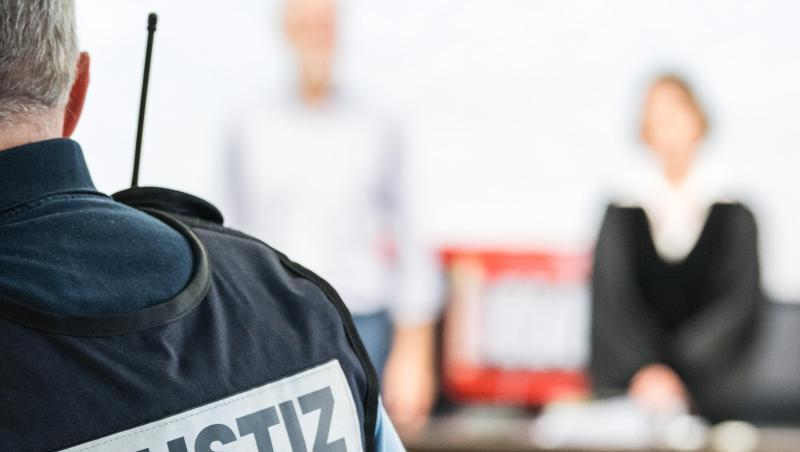 Ein Justizbeamter steht in einem Saal des Gerichtes. Foto: Sebastian Gollnow/dpa/Archivbild