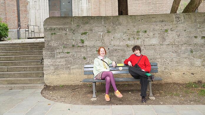 Designerin Ruth (23) und Model Liam (23) probieren das neue Ratschbankerl am St.-Anna-Platz im Lehel schon einmal aus. Von den speziell markierten Parkbänken gibt es jetzt in jedem Stadtbezirk eine.