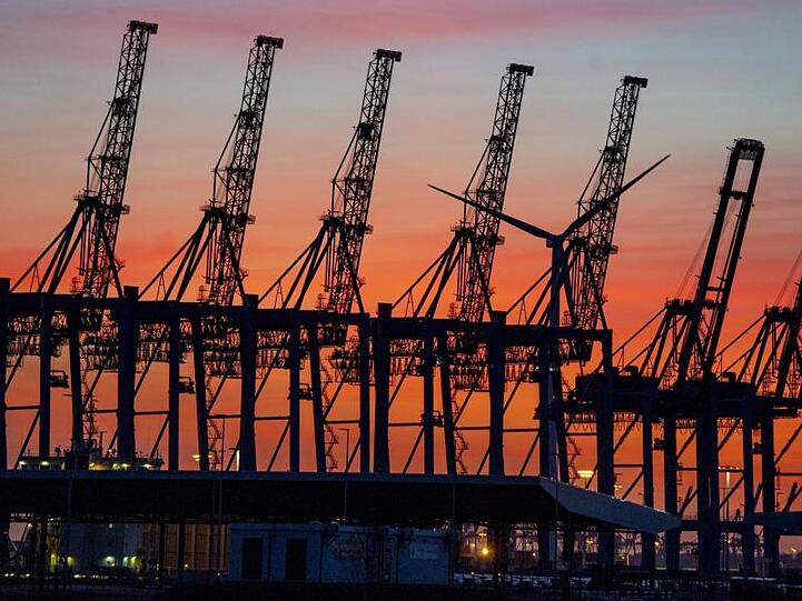 Hinter hochgeklappten Containerbrückenkränen im Hamburger Hafen geht die Sonne unter. Die Corona-Krise bremst den weltweiten Handel aus.
