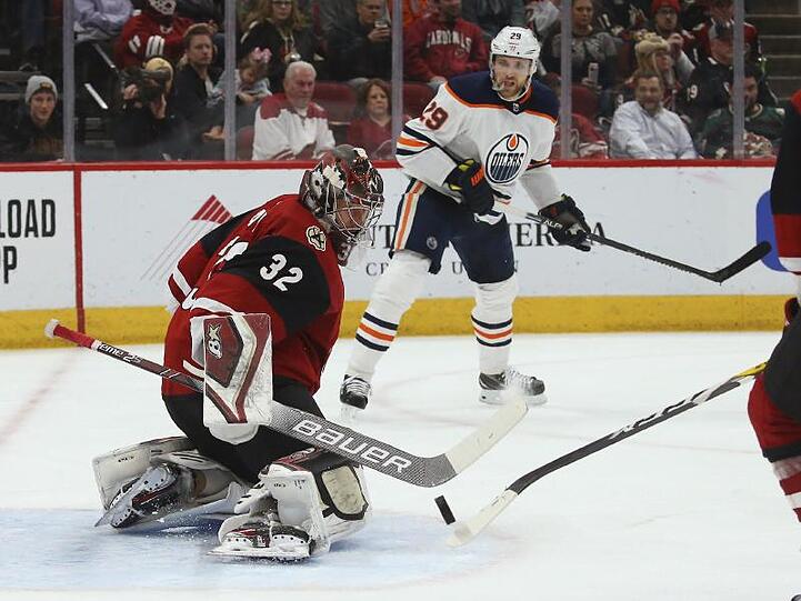 Coyotes-Torwart Antti Raanta (l) stoppt einen Schuss Leon Draisaitls (M) von den Edmonton Oilers.
