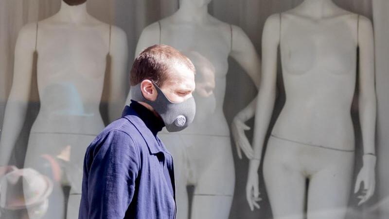 Ein Mann mit Schutzmaske läuft an einem Schaufenster mit Schaufensterpuppen, die Stoffmasken tragen, vorbei. Foto: Christoph Soeder/dpa/Archivbild Ein Mann mit Schutzmaske läuft an einem Schaufenster mit Schaufensterpuppen, die Stoffmasken tragen, vorbei. Foto: Christoph Soeder/dpa/Archivbild