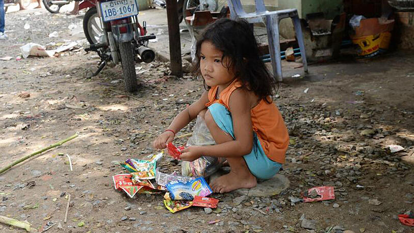 Ein armes Mädchen spielt in Phnom Penh mit Müll.