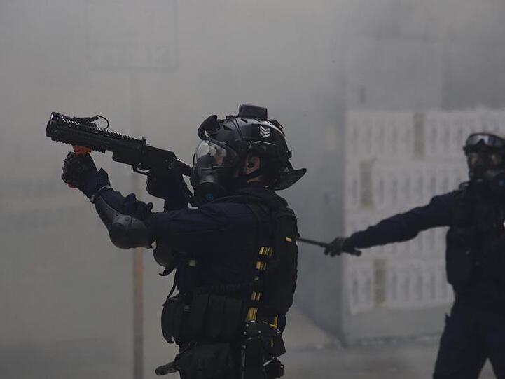 Ein Polizist zielt mit Tränengas auf Demonstranten bei regierungskritischen Protesten.