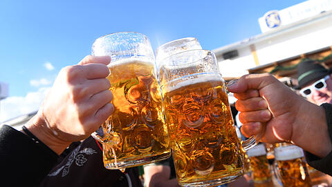 Bier-Maßkrüge die sich Zuprosten. (Symbolbild)