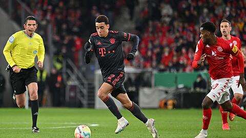 Schiedsrichter Deniz Aytekin (l) beobachtet den Münchner Jamal Musiala und den Mainzer Edmilson Fernandes im Zweikampf.